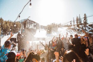 Group of skiers and snowboarders partying after skiing on Canyon Deck at Mammoth Mountain