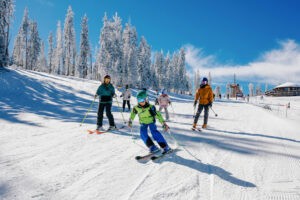 Family skiing down groomed ski runs on a bluebird day at Angel Fire Resort