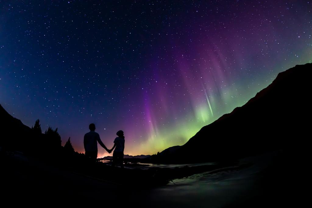 Couple holding hands while watching the Northern Lights