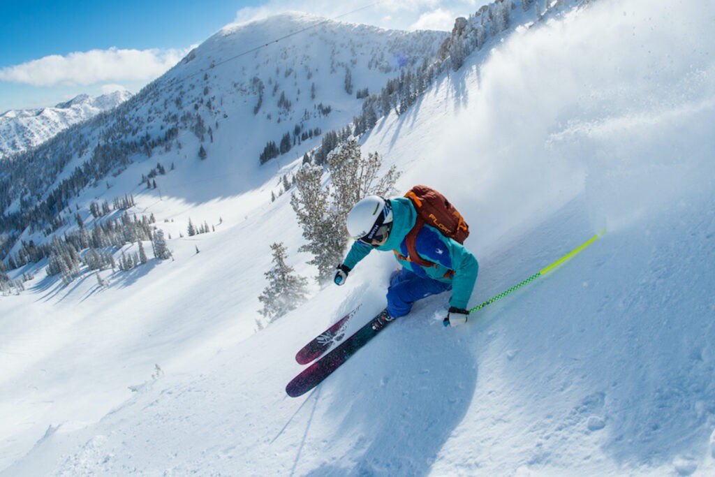 Skier skiing down Snowboard on a bluebird day to the backdrop of snow covered mountains