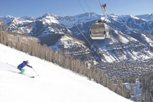 Skier skiing below Telluride gondola