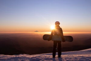 Snowboarder looking at Mount Taranaki at sunset from Turoa Ski Field