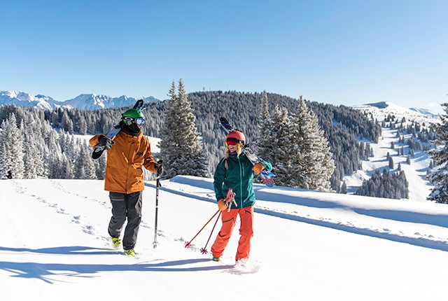 Two skiers holding skies on back bowls of Vail Resorts.